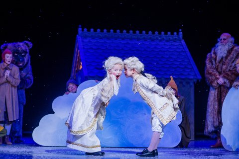 To små barn i 1700-tallskostymer og -parykker. De lener seg mot hverandre, og den ene hvisker noe inn i øret til den andre