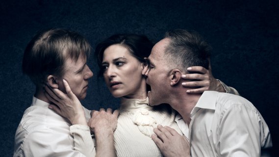 To menn flankerer en kvinne, de tar på hverandre. Den ene mannen biter kvinnen i halsen