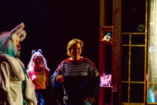 To skuespillere i kanin- og kattekostyme og mann i mariusgenser står på mørk scene og ler