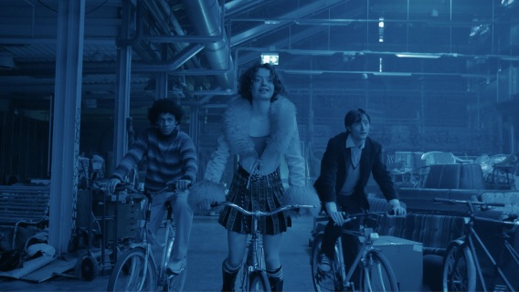 En kvinne og to menn på sykkel i en stor hall