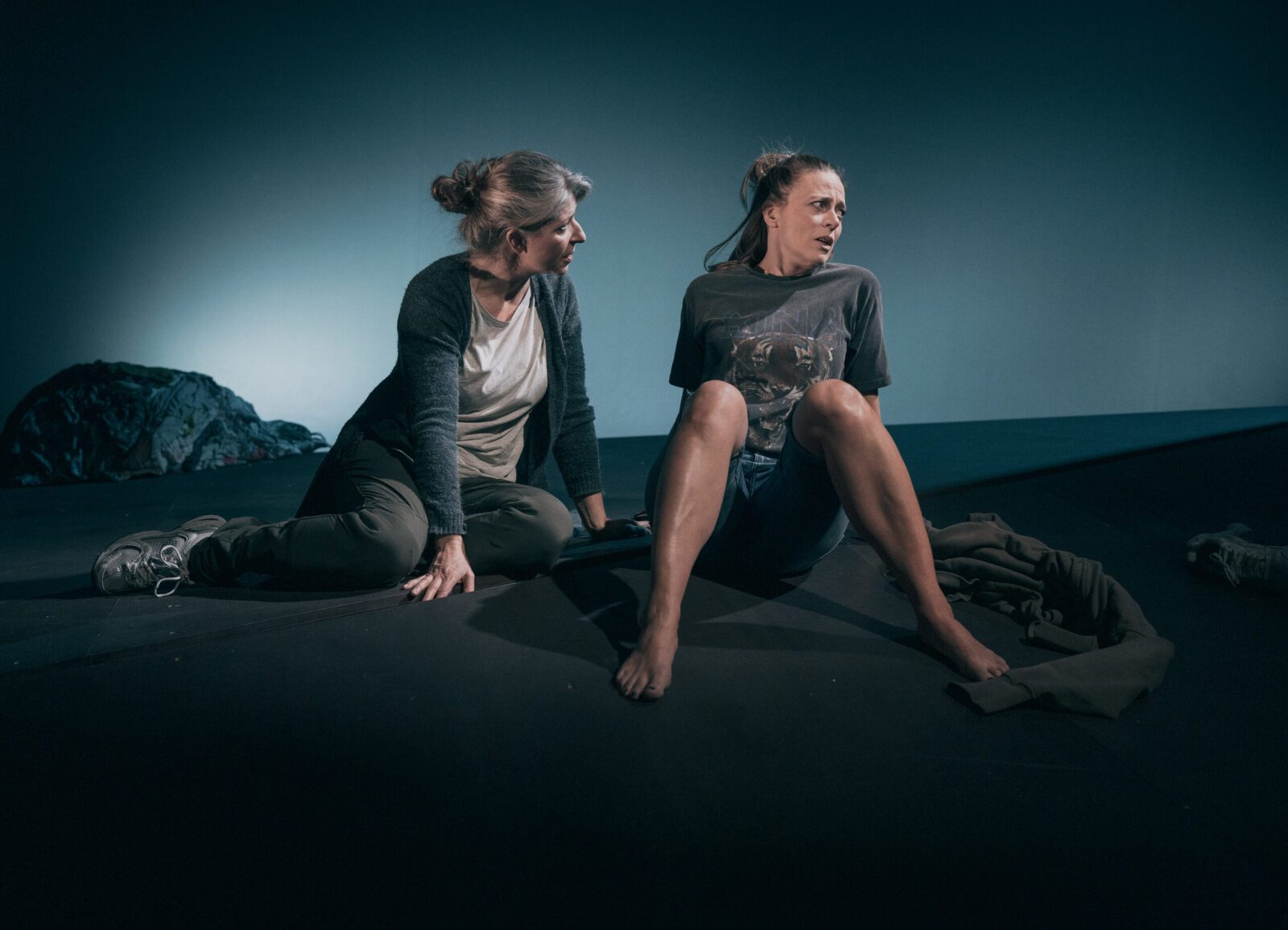 To kvinner sitter på en mørk scene