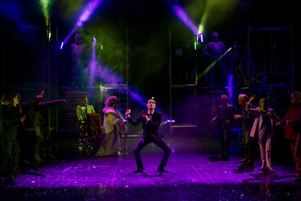 Mann i smoking danser i farget lys, mens folk danser rundt