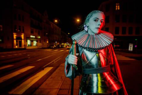 Kvinne i rustning i bybilde på kveldstid