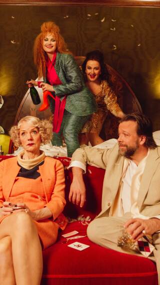 Fire skuespillere som herjer på et hotellrom. To kvinner hopper i senga, mens en kvinne og en mann sitter i sofaen