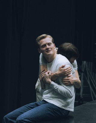 Svart hvitt-bilde av en kvinne som ser i kamera og støtter hodet i hånda