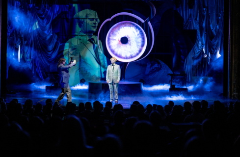 To menn på en scene med fullsatt sal