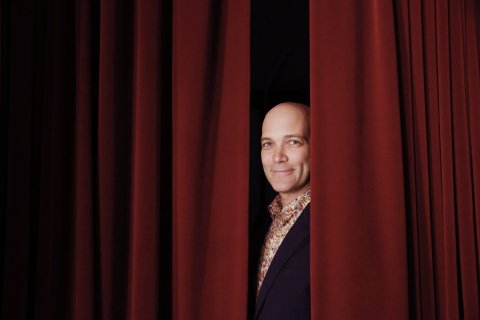 Portrait of a man behind red curtains